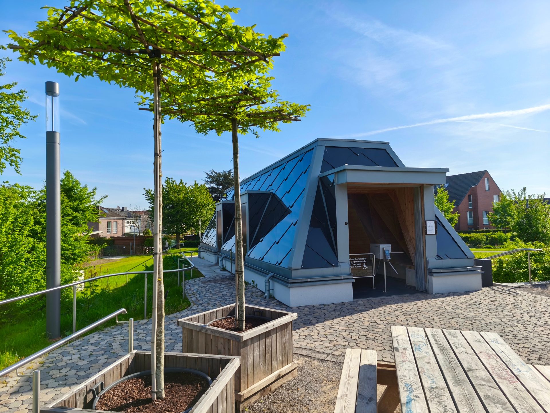 Widok na inhalatorium w ogrodzie solankowym St. Jakob w Kevelaer z miejscami do siedzenia wśród zieleni - miejsce do inhalacji i relaksu w słonym powietrzu.