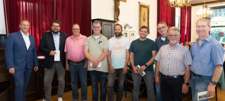 Kilku mężczyzn i kobiet stoi obok siebie i trzyma w rękach koperty.