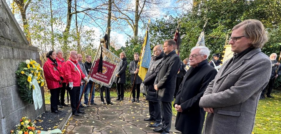 Członkowie klubów społecznych, lokalny burmistrz i burmistrz stoją przed pomnikiem w Marienpark