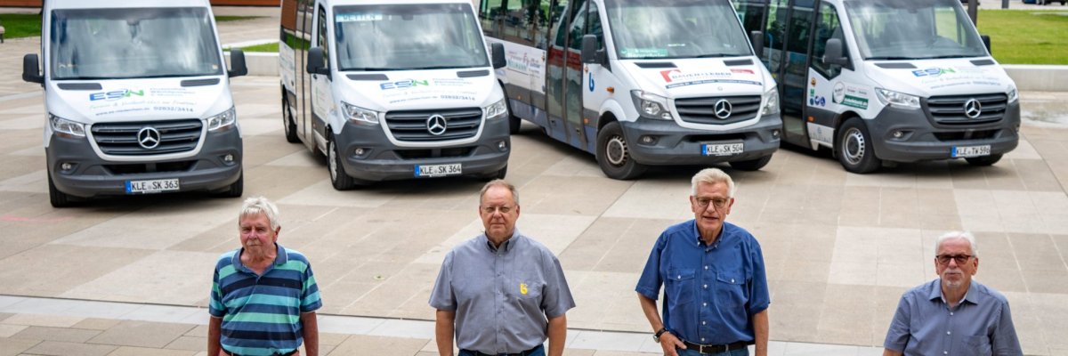 Czterech mężczyzn stoi przed czterema autobusami gminnymi w Kevelaer.