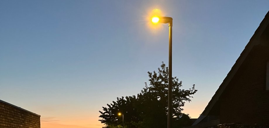 Leuchtende Straßenlaterne an einem Weg.