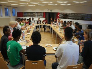 Ehrenamtliche und Geflüchtete an einem Tisch