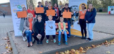 Unterstützende der weiterführenden Schulen und der Wallfahrtsstadt Kevelaer setzen mit orangefarbener Bank auf dem Schulhof am 25. November 2022 ein Zeichen gegen Gewalt an Frauen und Mädchen!
