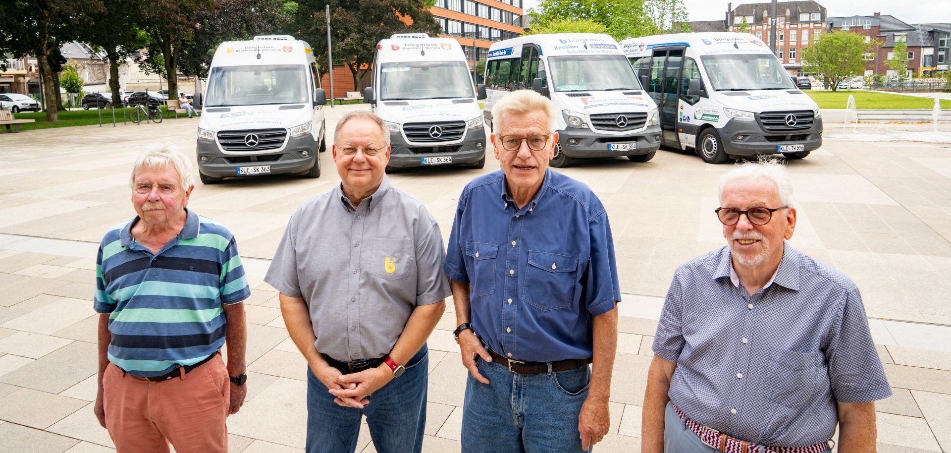 Vier Männer stehen vor den vier Bürgerbussen in Kevelaer. 