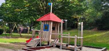 Spielplatz Heinestraße in Kevelaer Ein großes Holz-Klettergerüst mit einem Sandkasten auf einem Spielplatz.