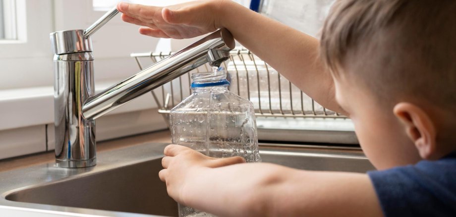 Ein Junge füllt eine Trinkflasche am Wasserhahn.