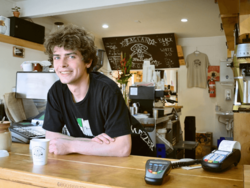 ein junger Mann steht hinter einer Theke in einer Kaffee Bar